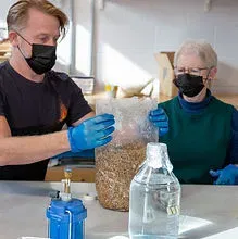 Two people introducing mycelium to a hemp mix during an Osmose Studio workshop